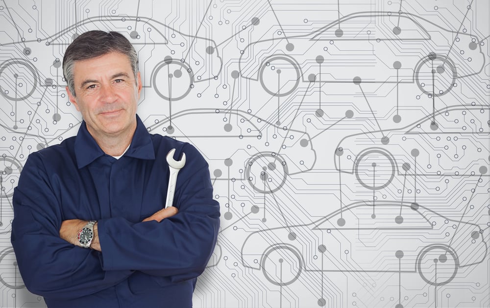 Mature mechanic standing in front of a cars diagram background while looking at camera